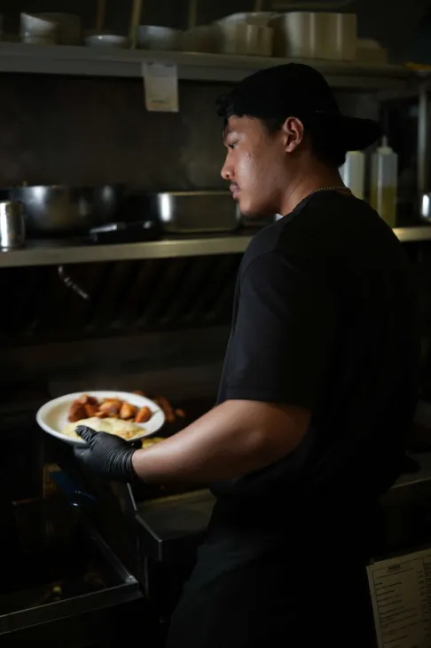 Avenue Open Kitchen cook plating an order behind the line